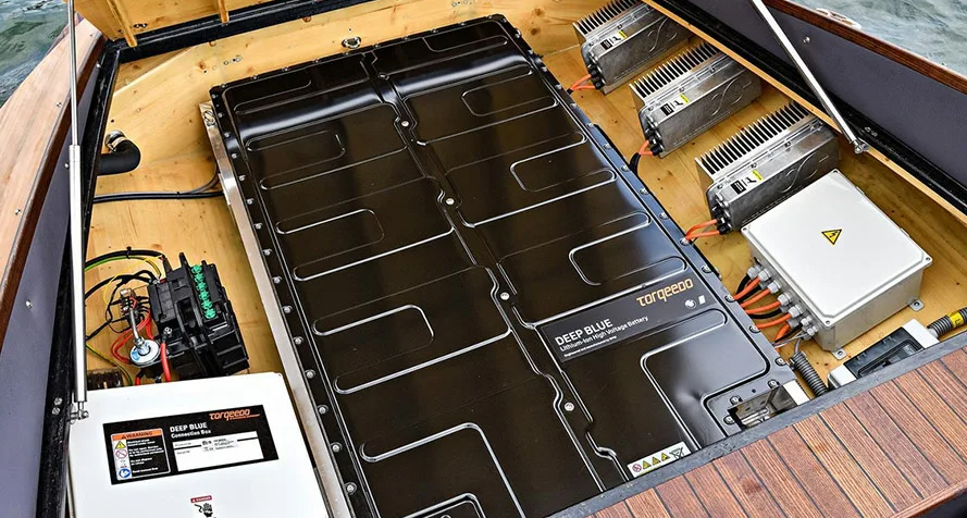 Technician servicing marine battery system for yacht conversion